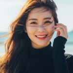 해변 근처에서 바람을 맞으며 머리카락이 흩날리는 모습