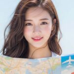 해변에서 바람에 머리가 날리며 여행 지도를 펼쳐 보는 모습