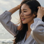 바닷가에서 머리카락을 정리하며 옆을 보는 모습