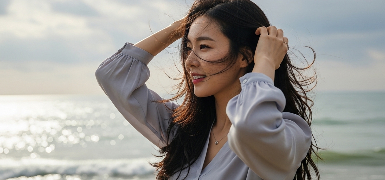 바닷가에서 머리카락을 정리하며 옆을 보는 모습